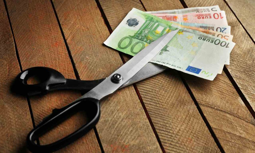 Scissors cut euro banknotes on wooden background